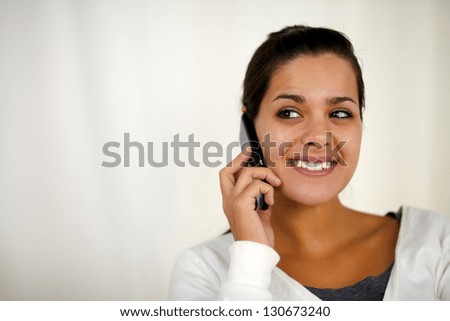 Portrait of a smiling young woman speaking on cellphone while is looking to her right - copyspace