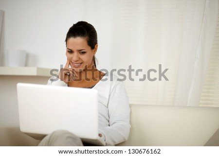 Portrait of a young female browsing the internet on laptop computer at home indoor