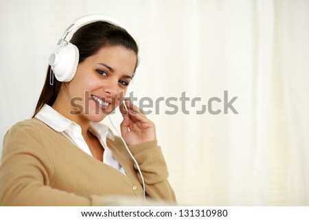 Portrait of a pretty young woman with headphone listening music and looking at you