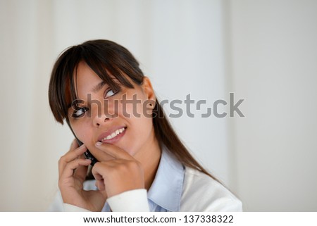 Portrait of a pensive young woman looking up speaking on cellphone at soft colors composition - copy space