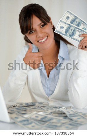 Portrait of a charming young woman with plenty cash dollars looking at you and showing you ok sing