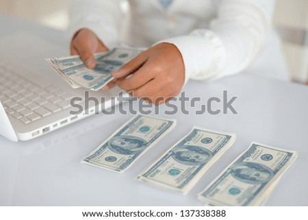 Portrait of a charming young woman counting cash money for buying on the internet