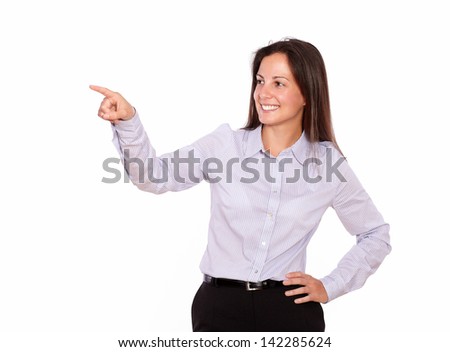 Portrait of a smiling young lady pointing to her right while standing on white background - copyspace