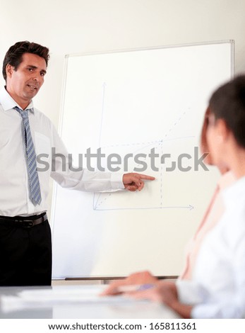 Portrait of a mature businessman working on his presentation while standing in front of white board