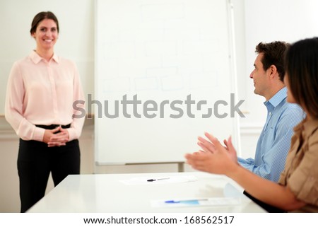 Portrait of professional business people giving applause at a meeting to colleagues in front of whiteboard
