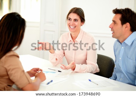 Portrait of professional executive team speaking at meeting while smiling and sitting on office desk