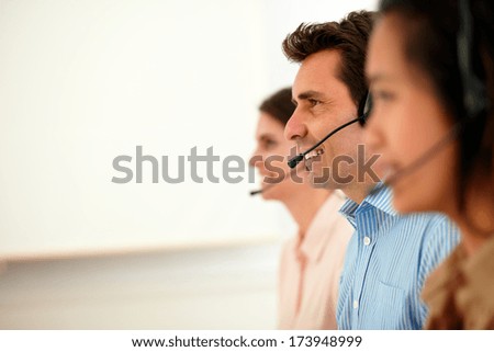 Portrait of beautiful and handsome operators with headphones giving service to the customer while sitting on workplace - copyspace