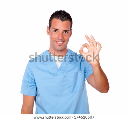 Portrait of handsome latin nurse on blue medical uniform with ok sign smiling at you while standing on isolated studio