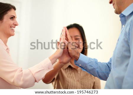 Portrait of man and women huddle their hands as unity sign while smiling and standing on office background