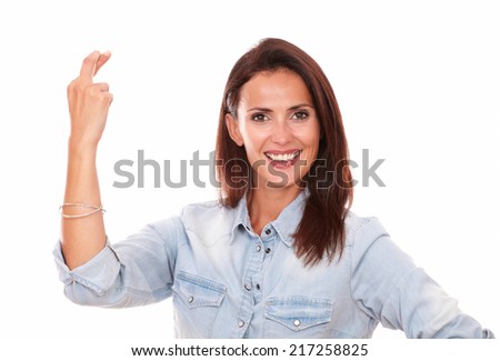 Portrait of friendly hispanic woman on blue blouse with lucky sign smiling at you while standing on isolated studio