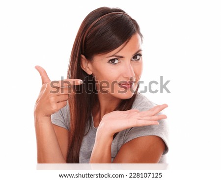 Portrait of beautiful woman pointing to her left and holding her palm up while smiling at you on isolated studio - copyspace