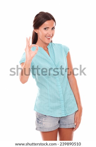 Hispanic girl in blue blouse gesturing a great job while looking at you and smiling in white background