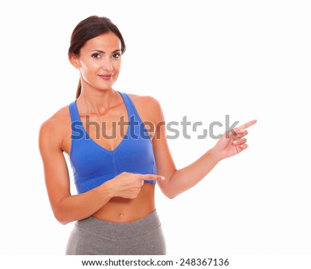 Adult woman training with vitality and pointing to her left on isolated background - copyspace