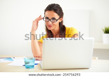 Smiling woman with spectacles working on the computer for a corporate company