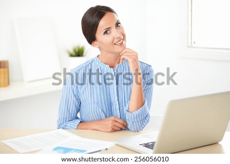 Pretty hispanic female in blue blouse studying on her desk at indoor