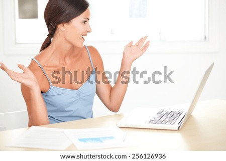 Lovely woman in blue blouse working on her desk and looking happy