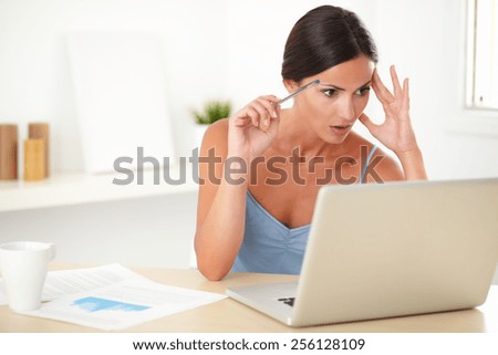 Lovely woman in blue blouse feeling pressured while looking at her laptop at work