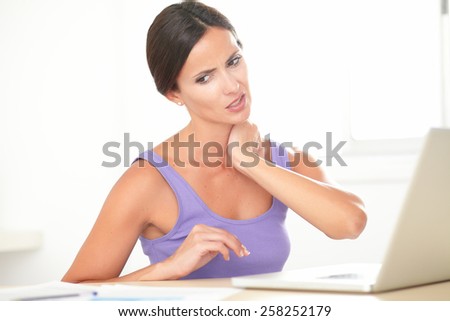 Pretty woman with neck pain working at home on her computer