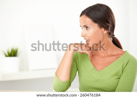 Adult pretty woman in green shirt with natural beauty looking shocked to her right at indoor - copyspace