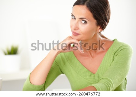 Pretty lady in green shirt with natural beauty smiling sincerely at home