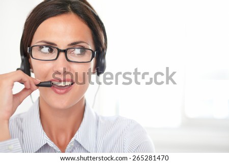 Confident young secretary in blue blouse talking on headphones in a callcenter - copyspace