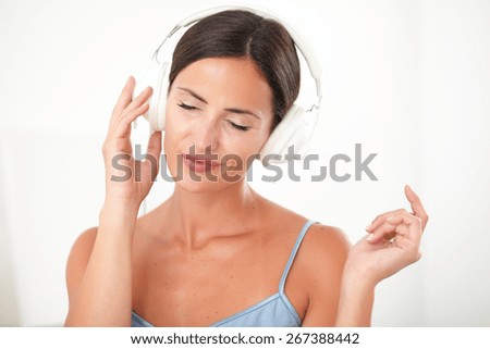 Smart woman with closed eyes in blue blouse chilling out by listening to music at her house