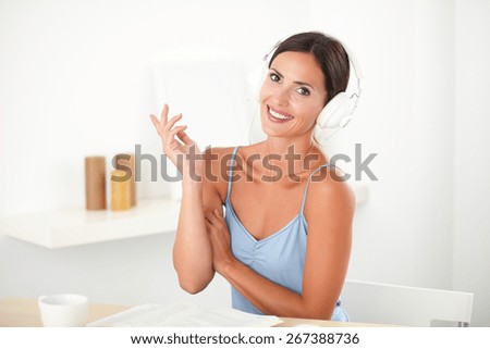Pretty happy woman in blue blouse listening to music on headphones at indoor