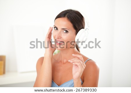 Lovely latin woman smiling while listening to music on headphones at indoor