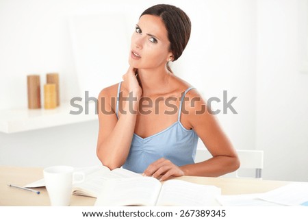 Attractive woman in blue shirt looking fatigued while reading her books at home