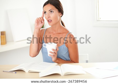 Sophisticated woman studying her books and looking up while wondering in her room