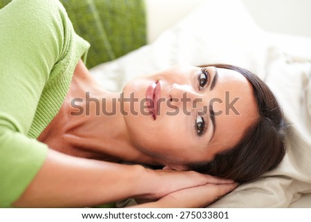 Peaceful young woman with straight hair lying on her back while looking at the camera with focus on foreground