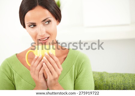 Thoughtful woman with pulled back hair holding a yellow mug while looking away - copy space