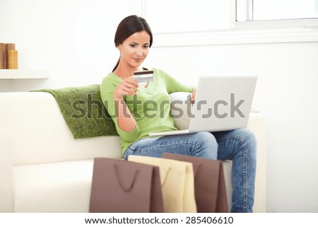 Young woman with brown hair using a credit card for home shopping - focus on foreground