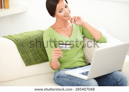 Three quarter length portrait of a beautiful female holding a credit card while using a laptop