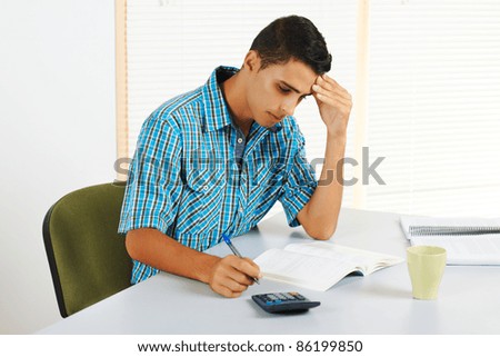 Young man trying to study with a headache.