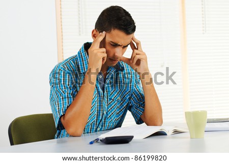 Young man trying to study with very strong headache.