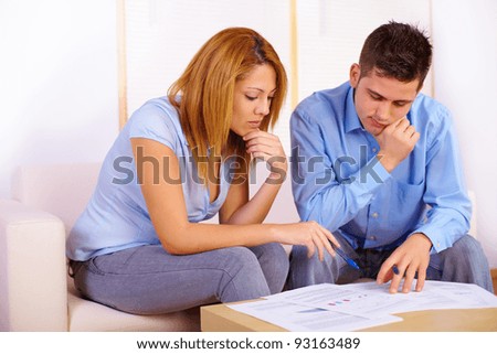 Portrait of a young couple reading documents on the living-room.