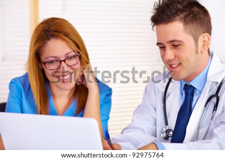 Portrait of a young doctor and a nurse talking and using a laptop on the office.