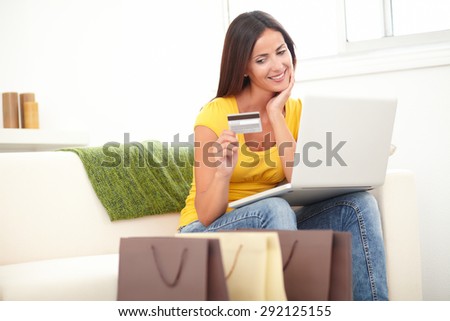 Confident woman in yellow shirt using a credit card for shopping from home