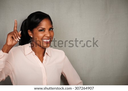 Happy businesswoman in formal clothing toothy smiling at the camera while pointing up