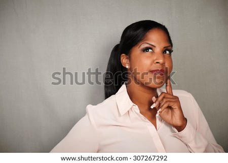 Reflective woman of afro-american ethnicity contemplating with hand on chin