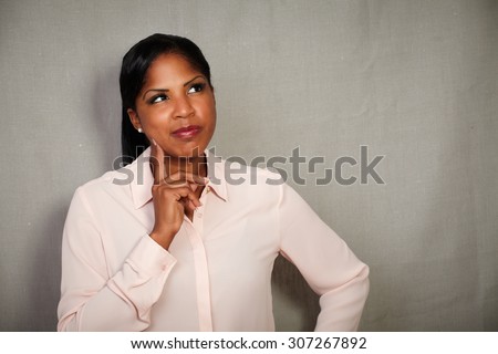 Young businesswoman in button down shirt planning with hand on chin - copy space