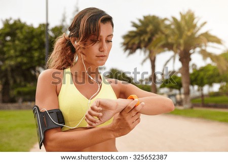 Horizontal portrait of a young runner 20-24 years old looking at smart watch