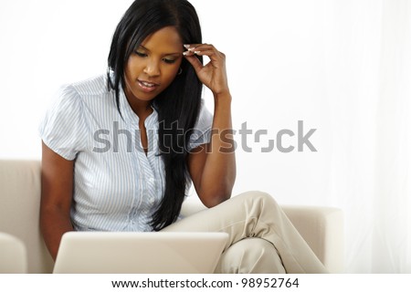 Portrait of a pretty young black woman browsing the web on laptop at home