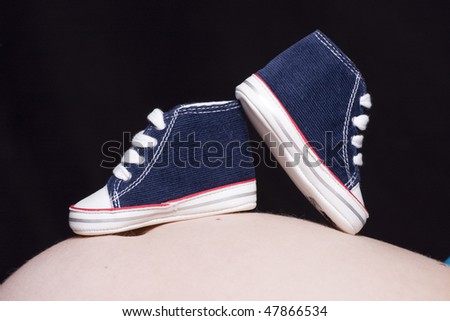 two shoes uploaded to the belly of a mother