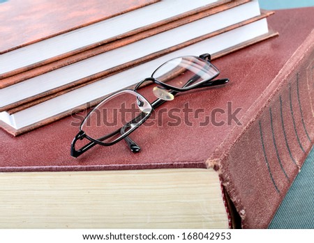 Pile of books and glasses on old thick volume
