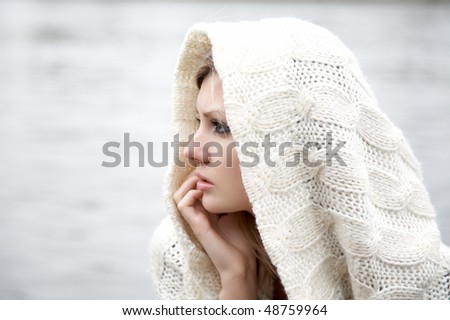 The thoughtful girl in  knitted dress on a background of water