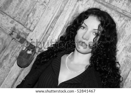 girl with black hair against a door with  lock the black-and-white