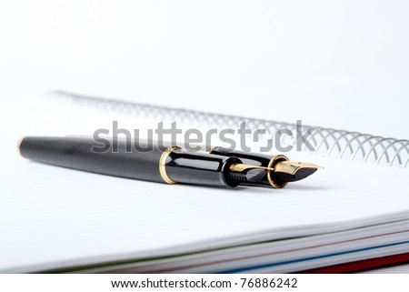 fountain pens lays on a writing-book with spiral