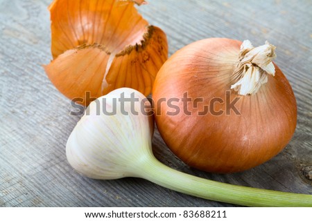 Garlic and onions with  peel on a table from unplaned boards